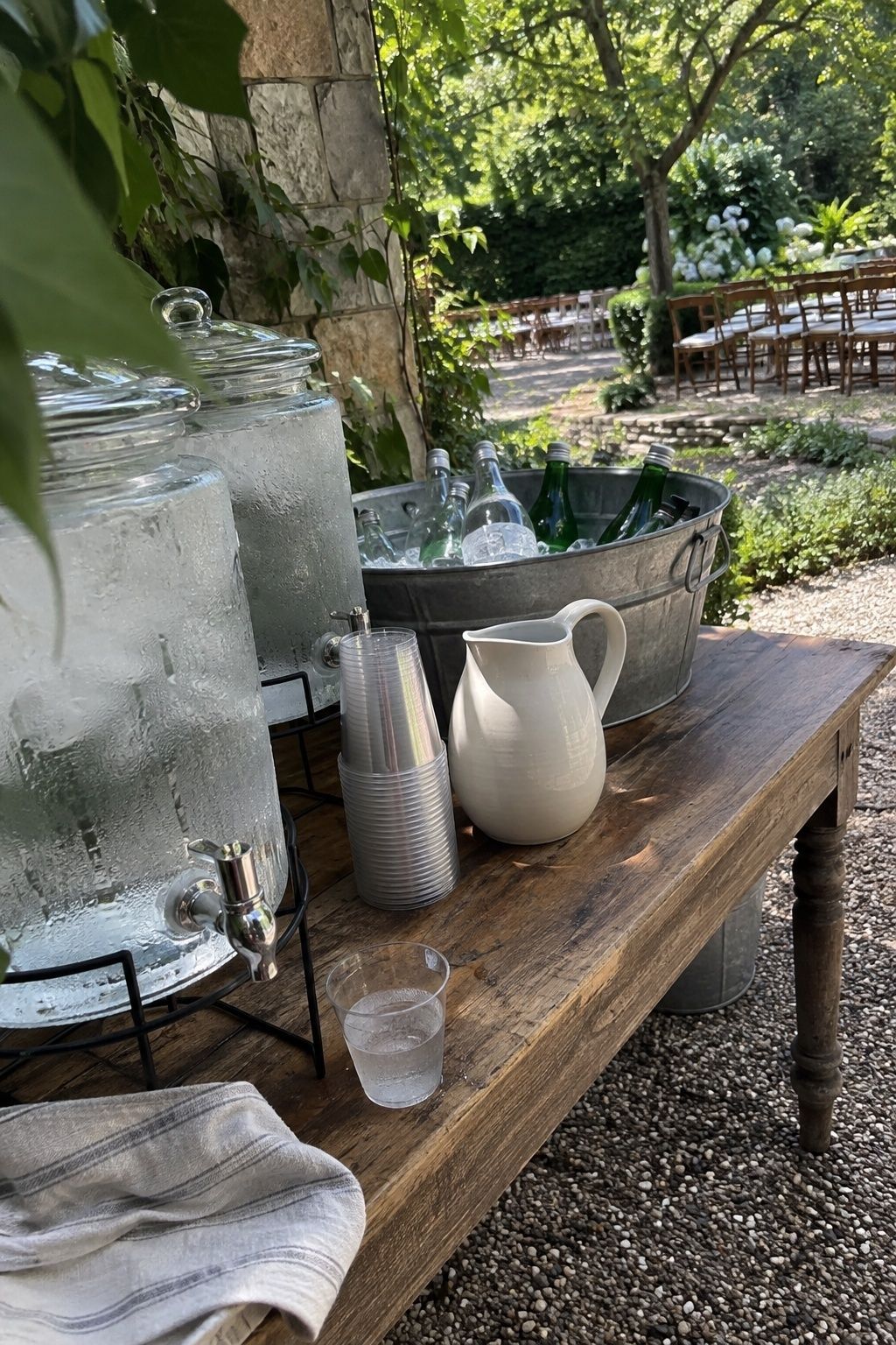 Shaded August wedding hydration station with cold water dispensers, chilled bottles and cups before the ceremony