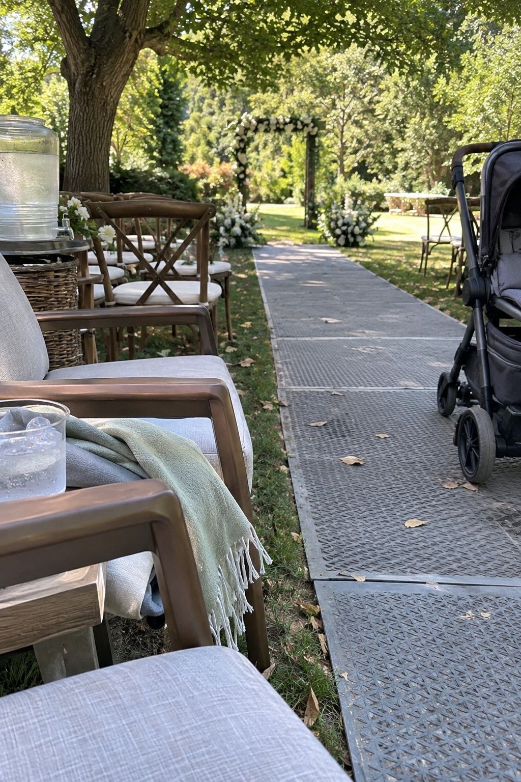 Shaded family seating with water, sturdy armchairs, stroller and a level access mat at an August wedding