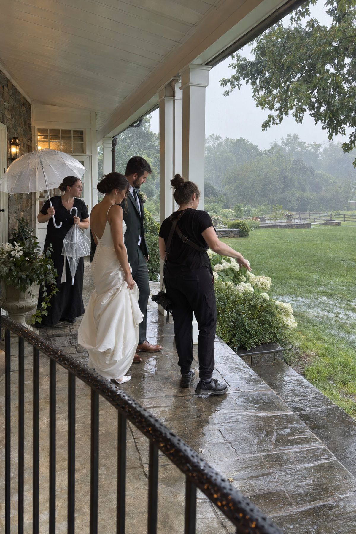 A couple and photographer check a covered portrait location during August rain.