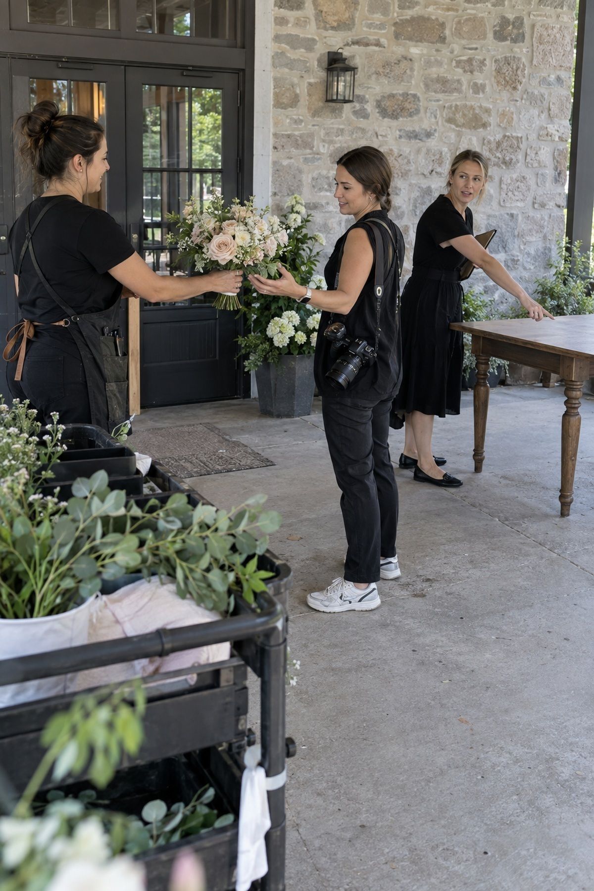 A florist hands an August bouquet to the photographer beside a clean detail table.