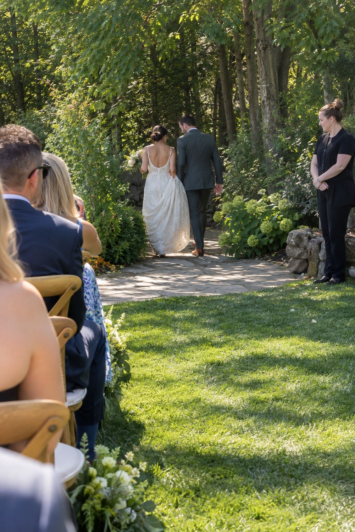 Newlyweds leave through a clear shaded path after an August wedding ceremony.