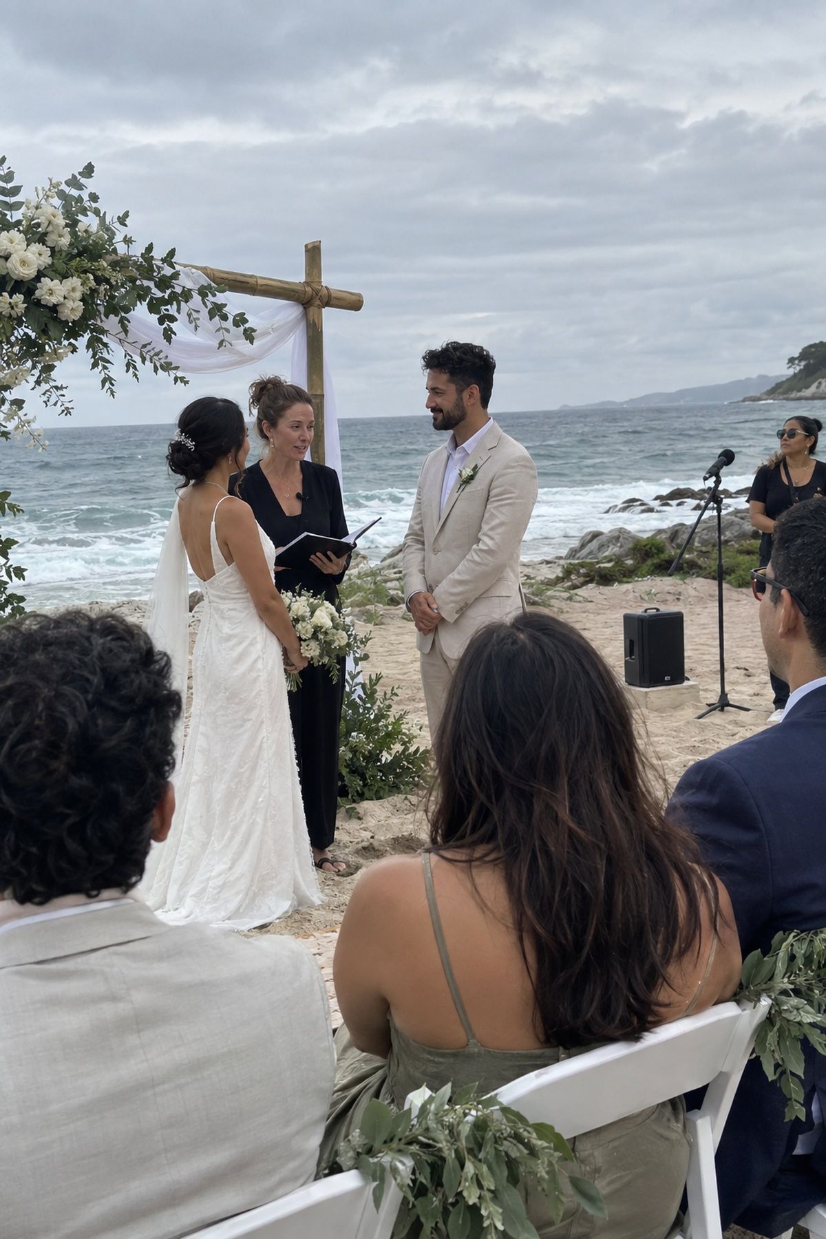 A beach wedding officiant uses a lapel microphone with compact sound equipment nearby.