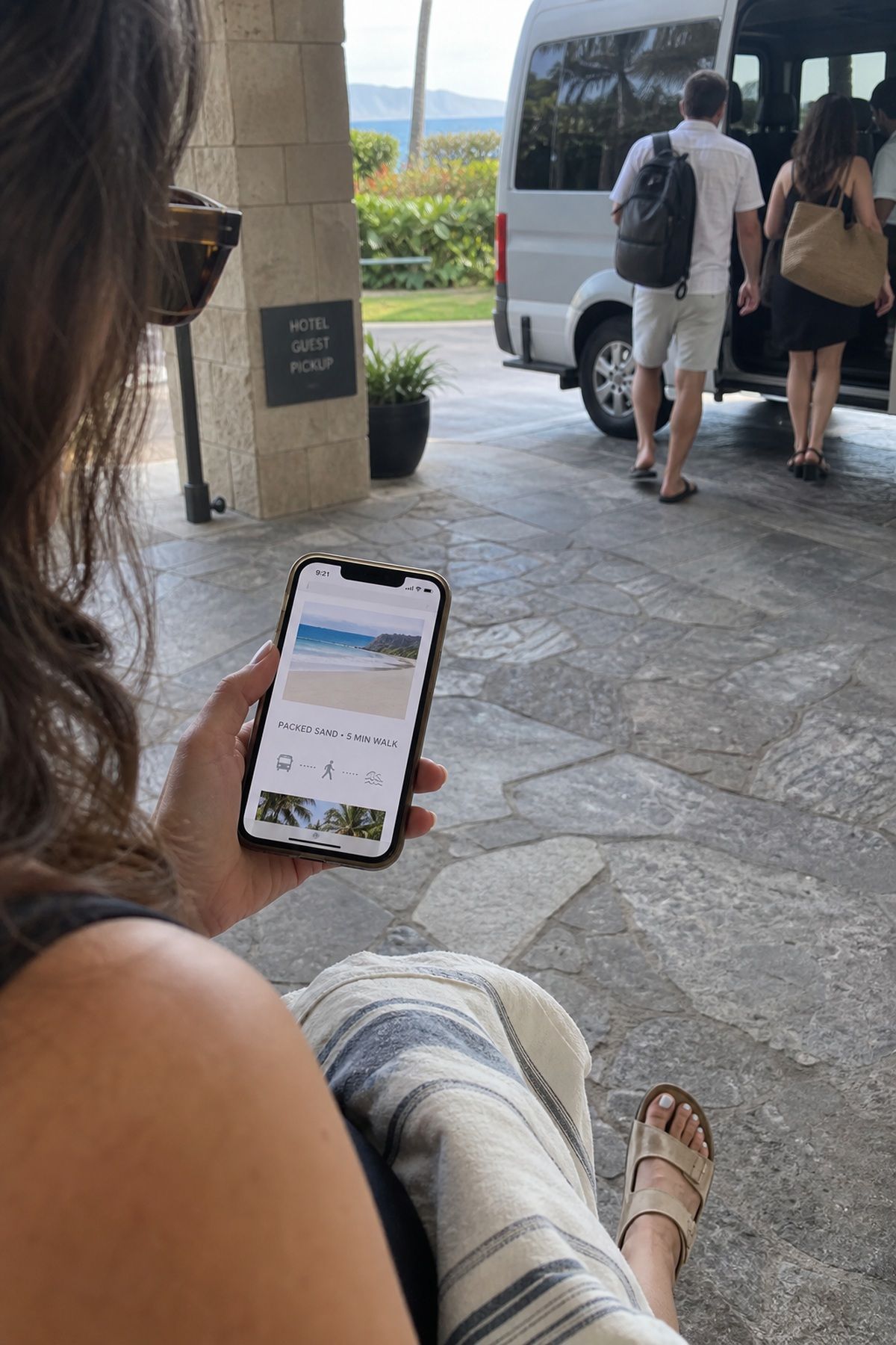 A wedding guest checks terrain and walking details on a phone before a beach ceremony.