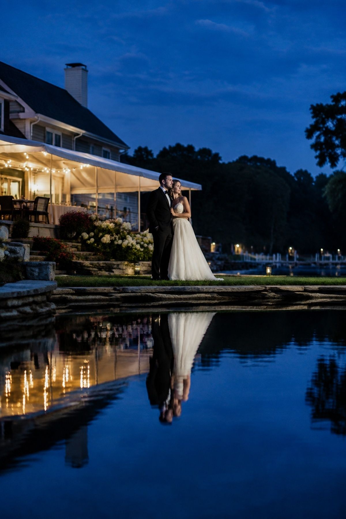 Blue hour waterfront wedding portrait with natural venue-light reflections on calm water