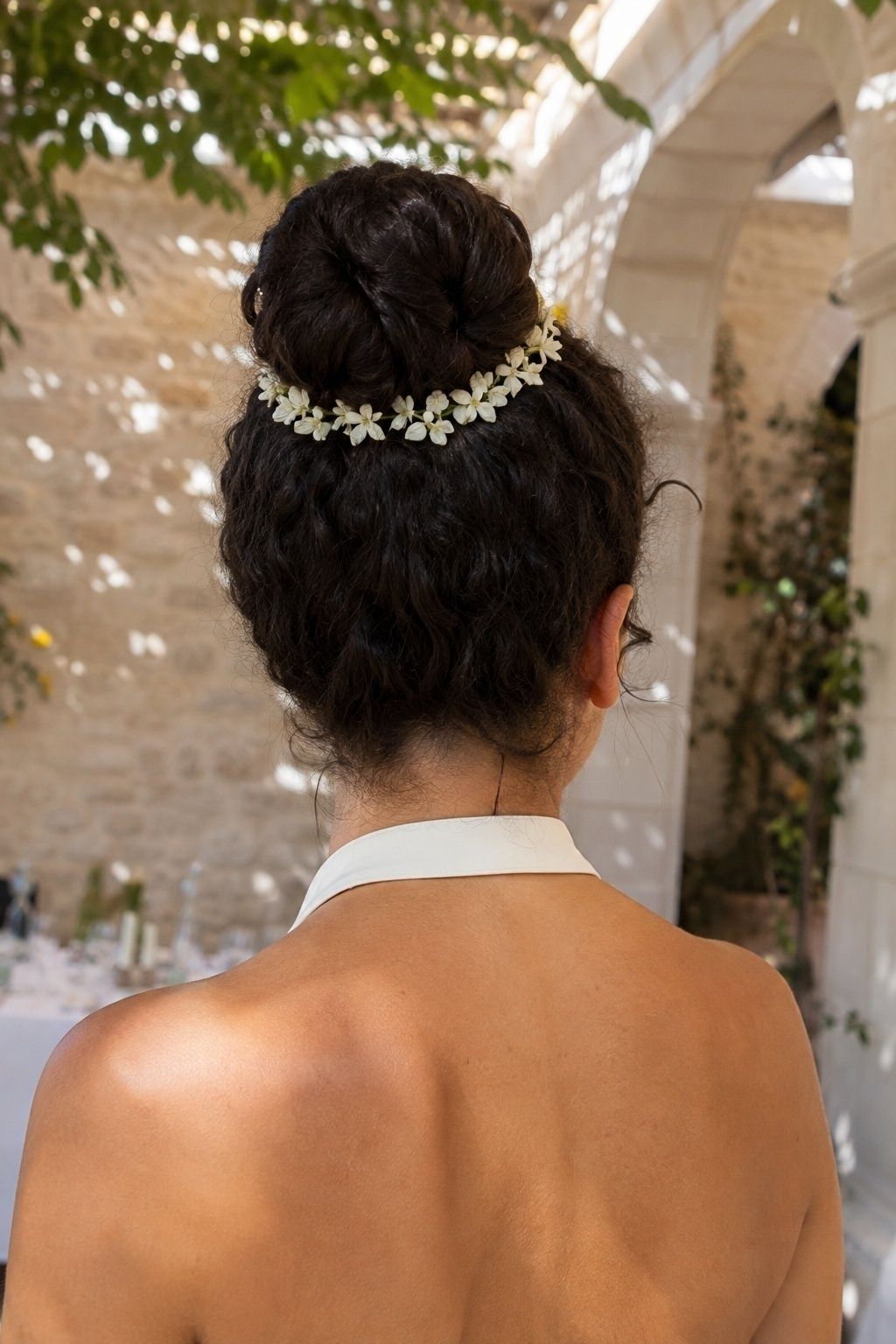 High bun wrapped with small white flowers