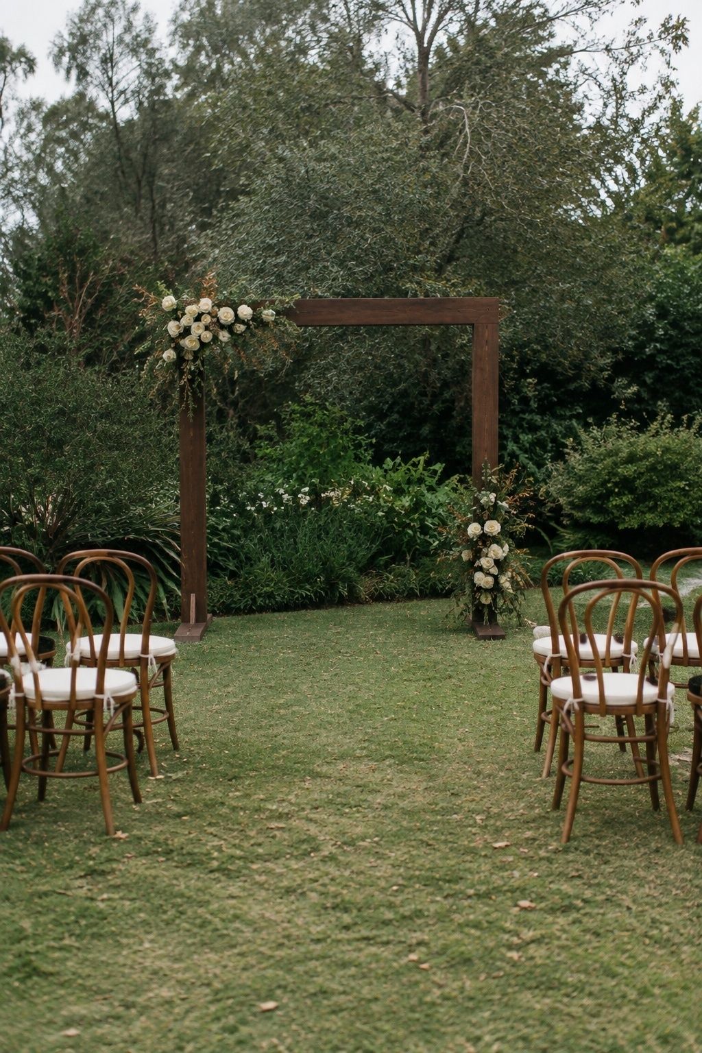 Walnut ceremony backdrop softened with florals