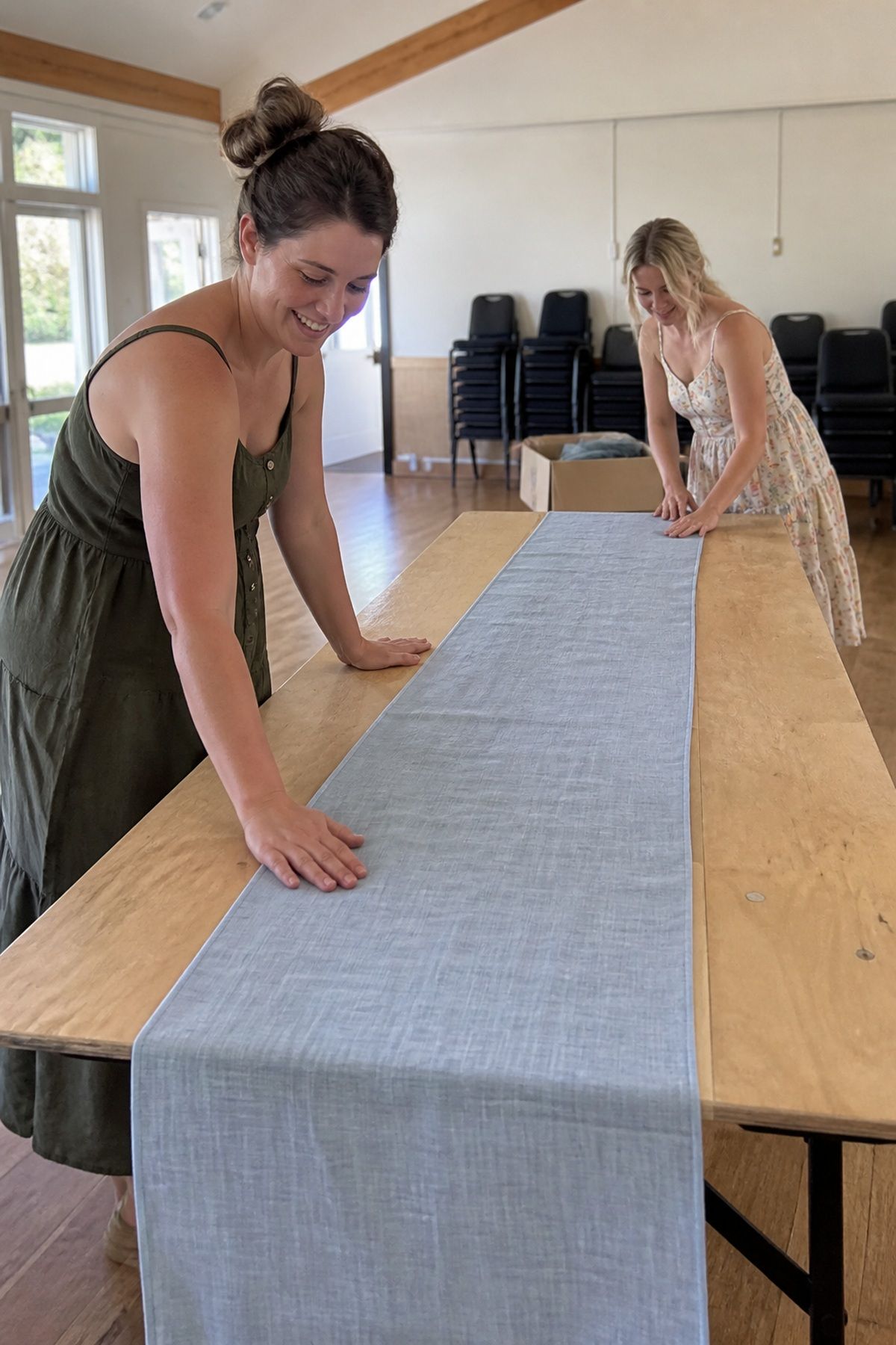 Two friends dress a simple wedding table with one pale-blue textured linen runner.