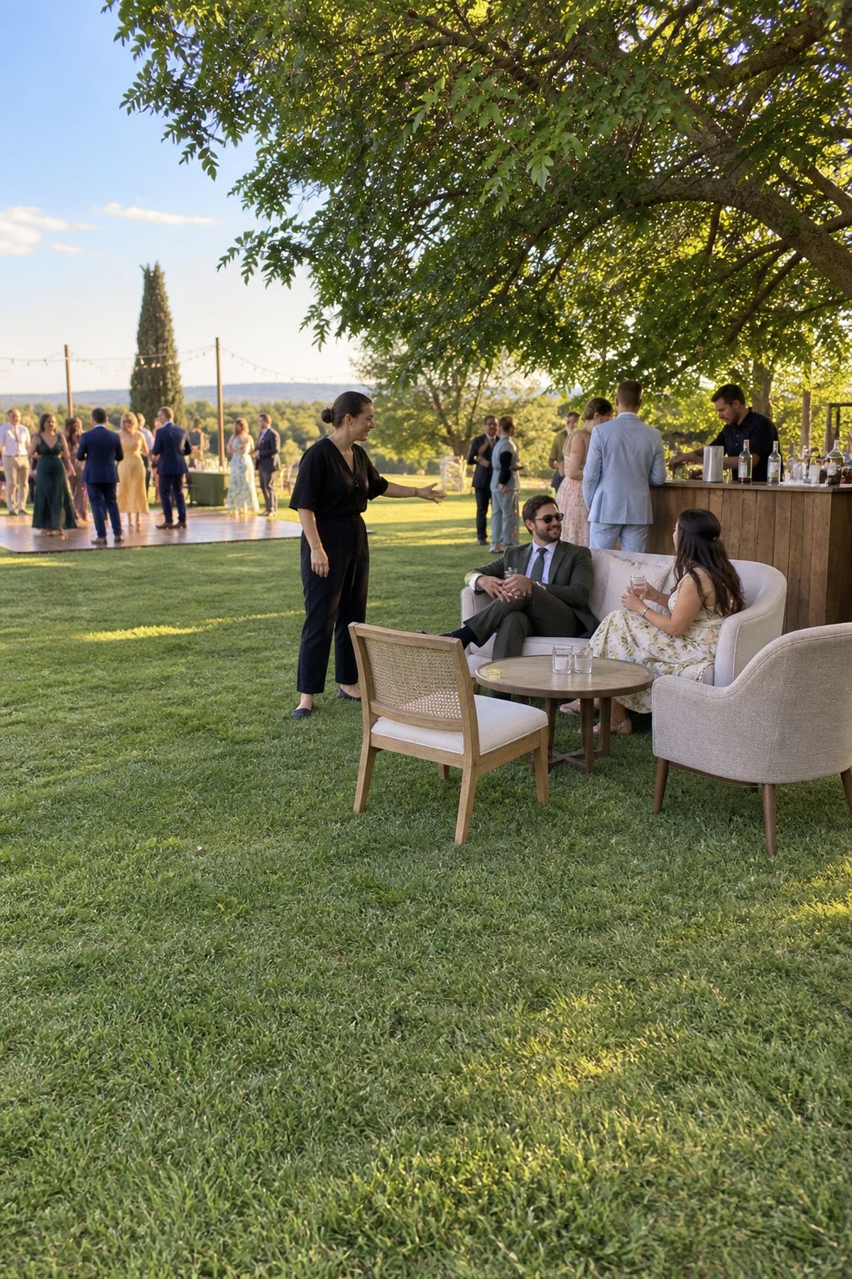 A compact rental lounge sits purposefully between the bar and dance area at a summer wedding.