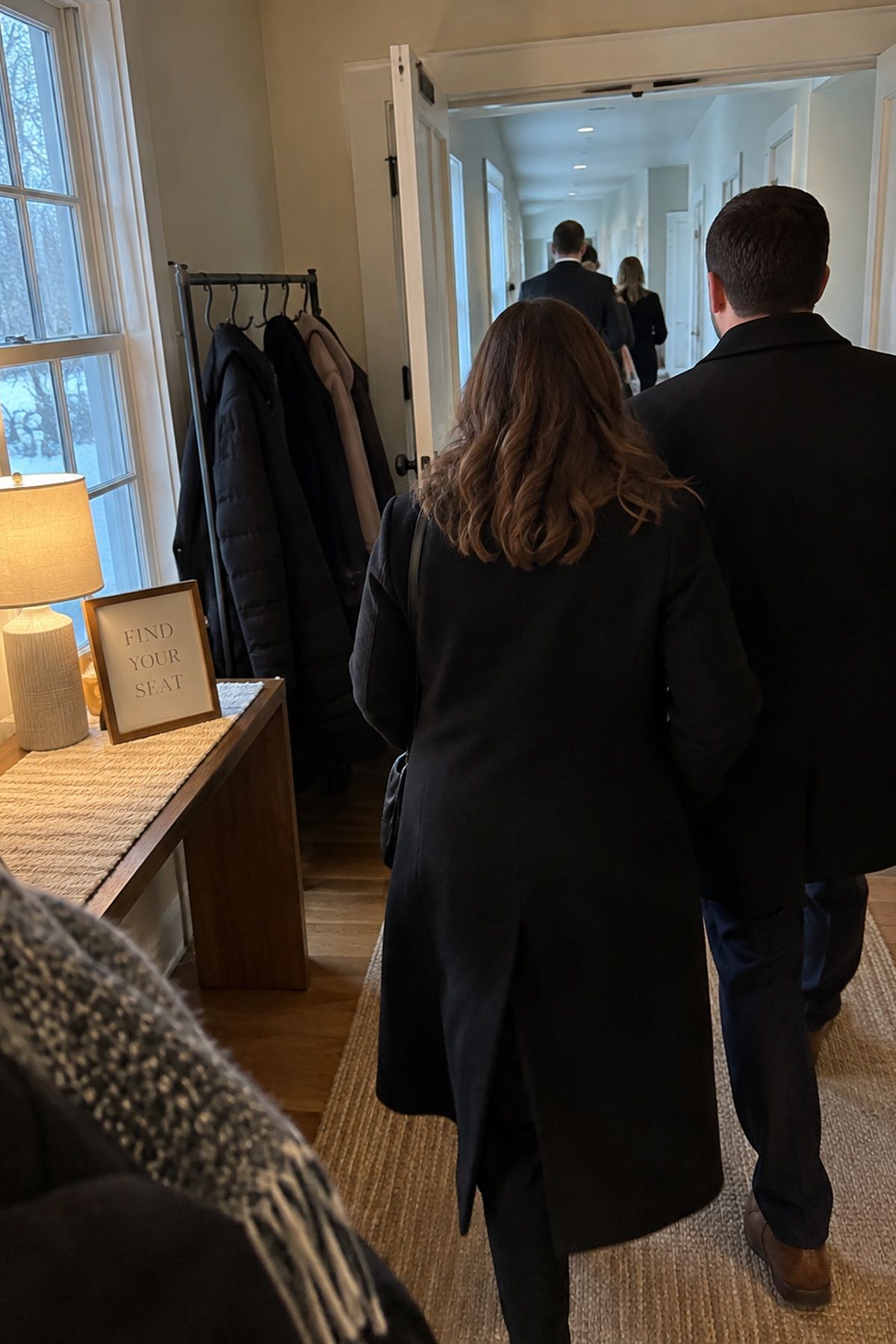 Winter wedding guests enter past a coat rack, warm lamp, and find your seat card in the first part of the venue.