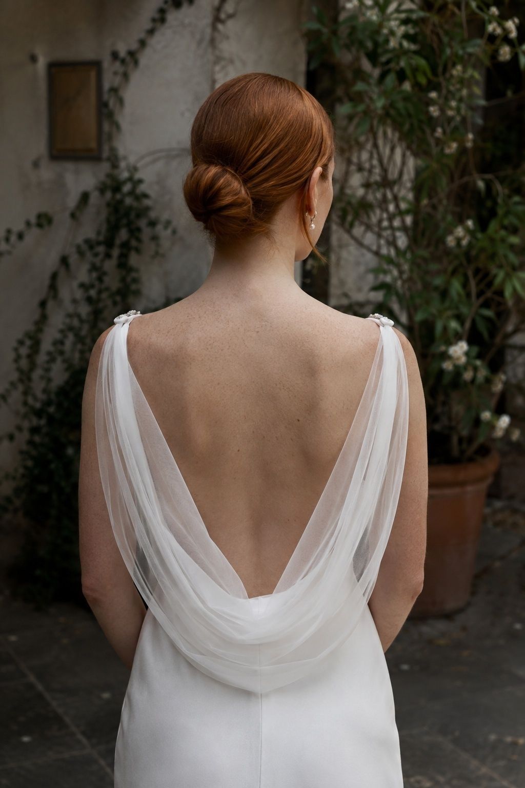 Low cowl cape veil framing the open back of a silk wedding gown.