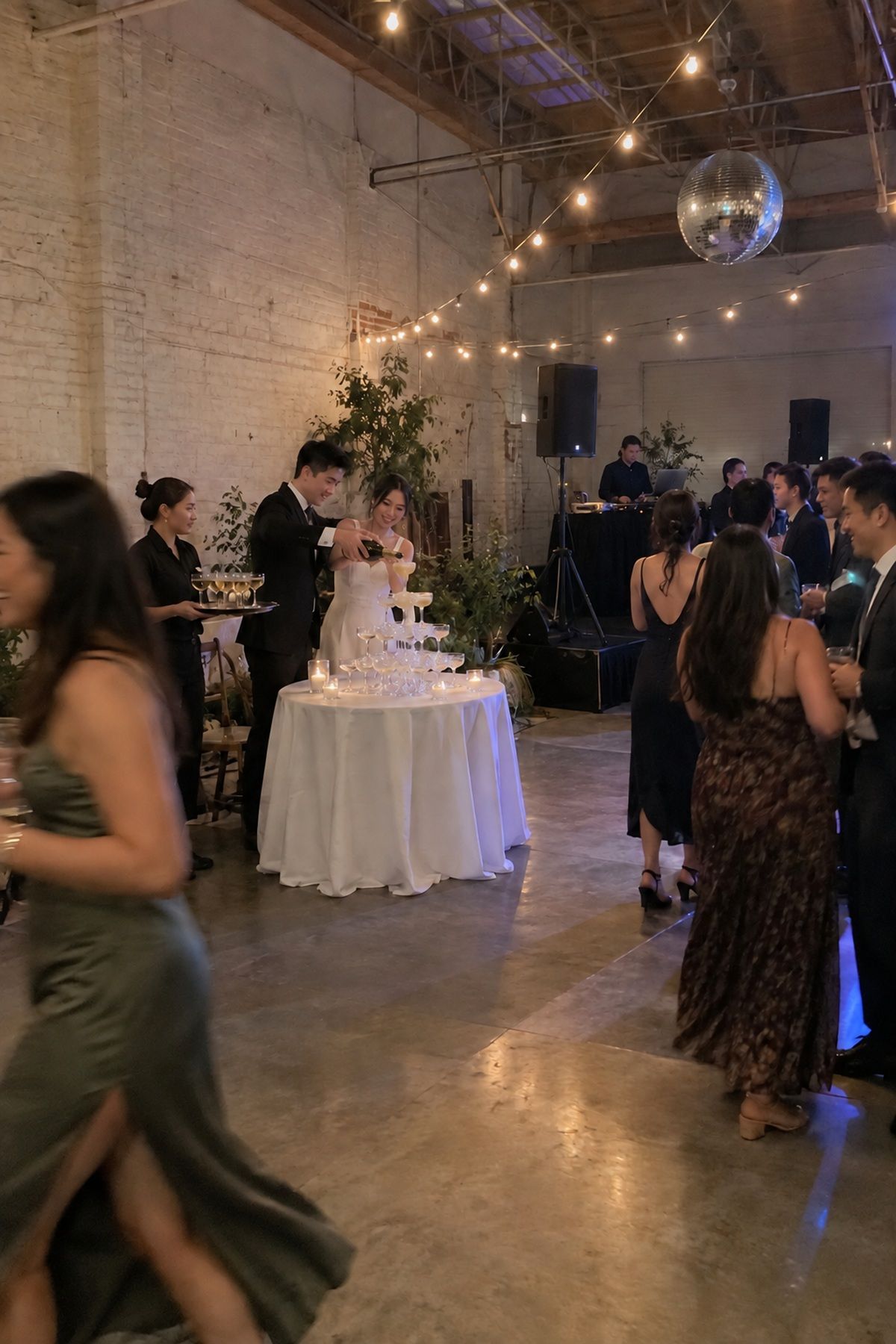 Simple reception lighting makes a late-night champagne tower pour clearly visible.