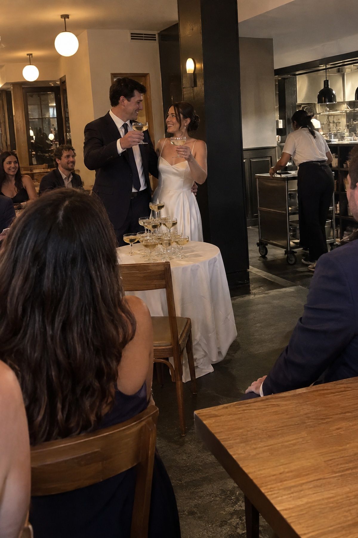A champagne tower toast follows dinner while the reception room resets for the next moment.