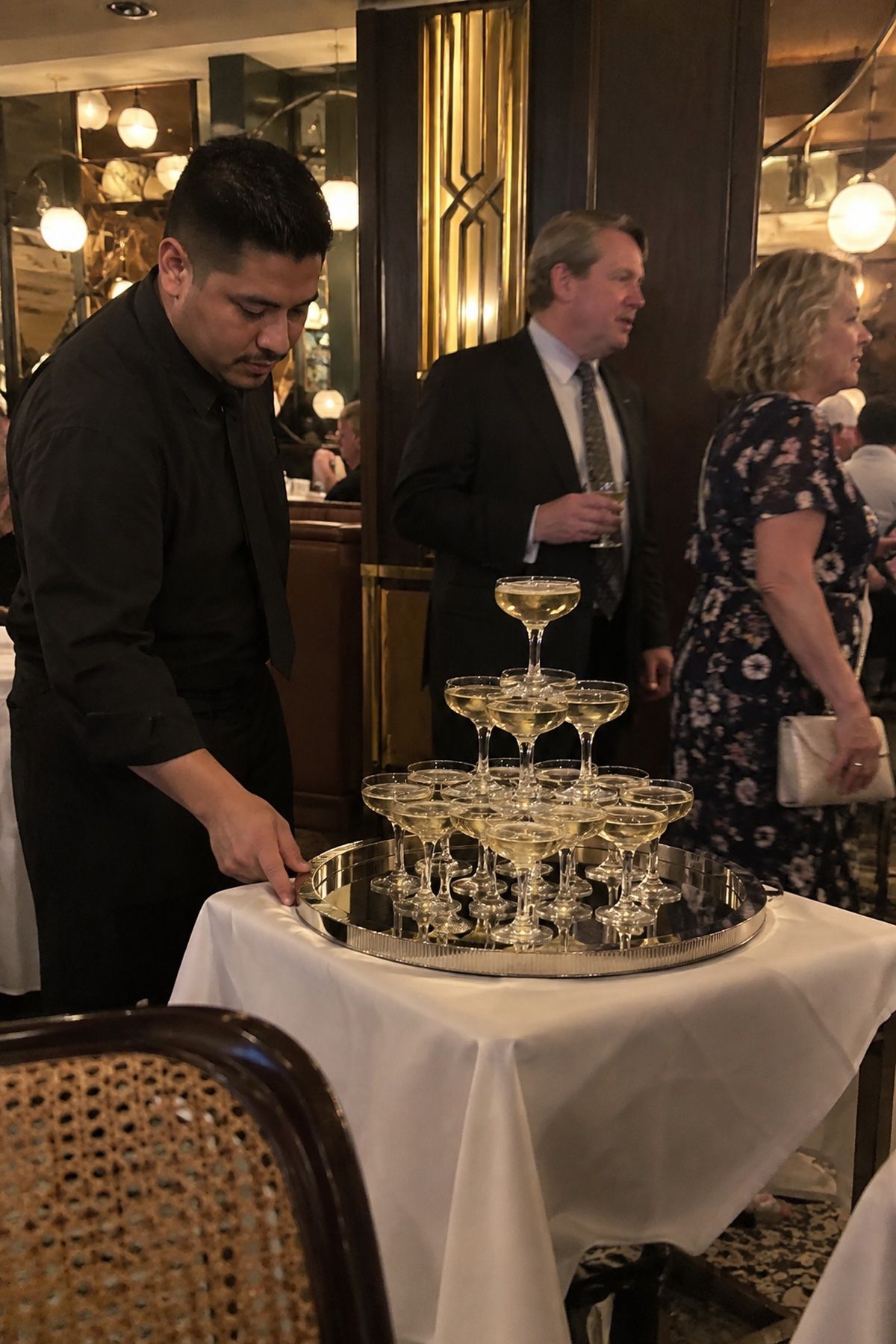A wedding bartender tends a mirrored champagne tower table during the reception.