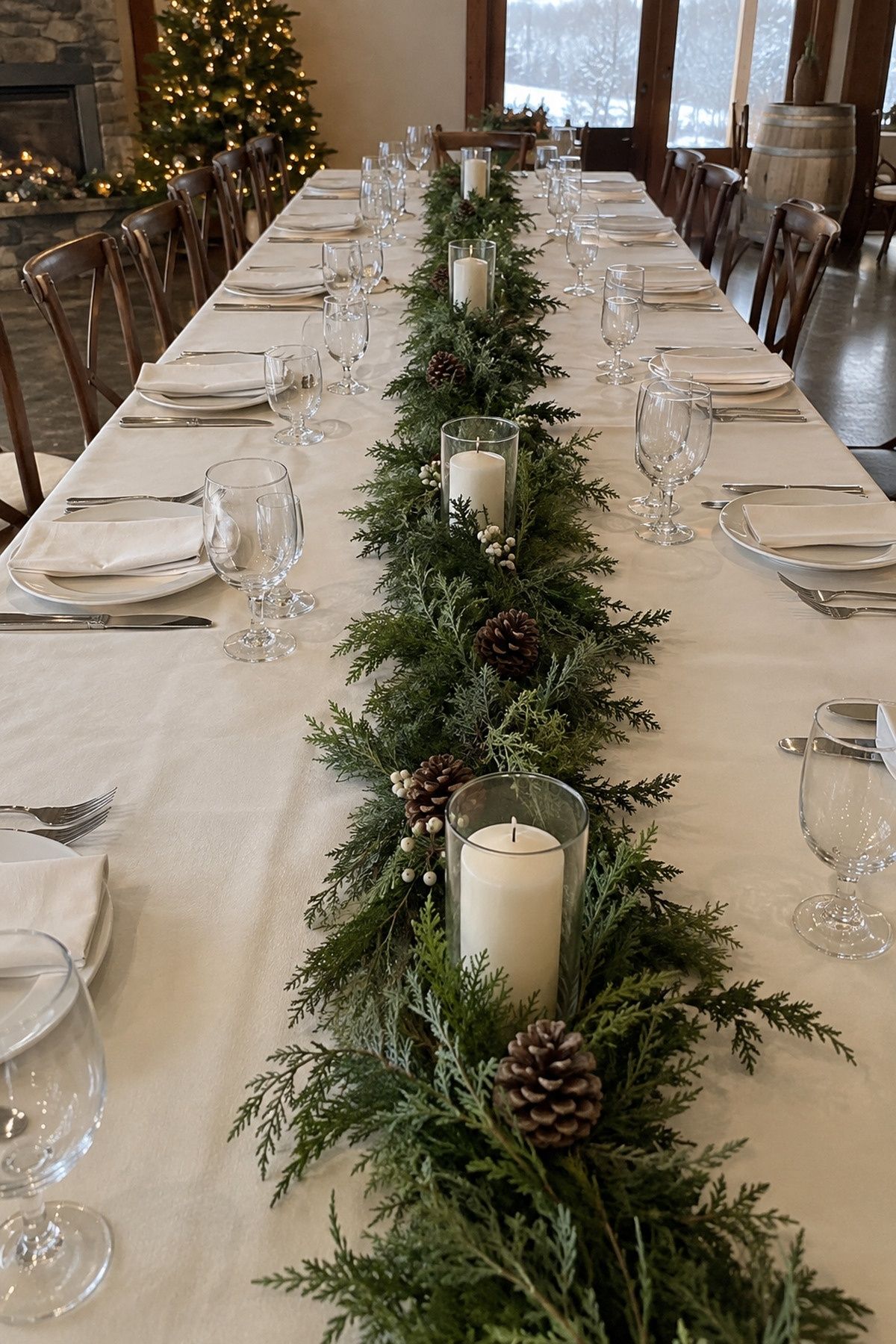 Narrow evergreen runner down the center of a cream-linen table, leaving clear place-setting edges at an intimate Christmas wedding reception