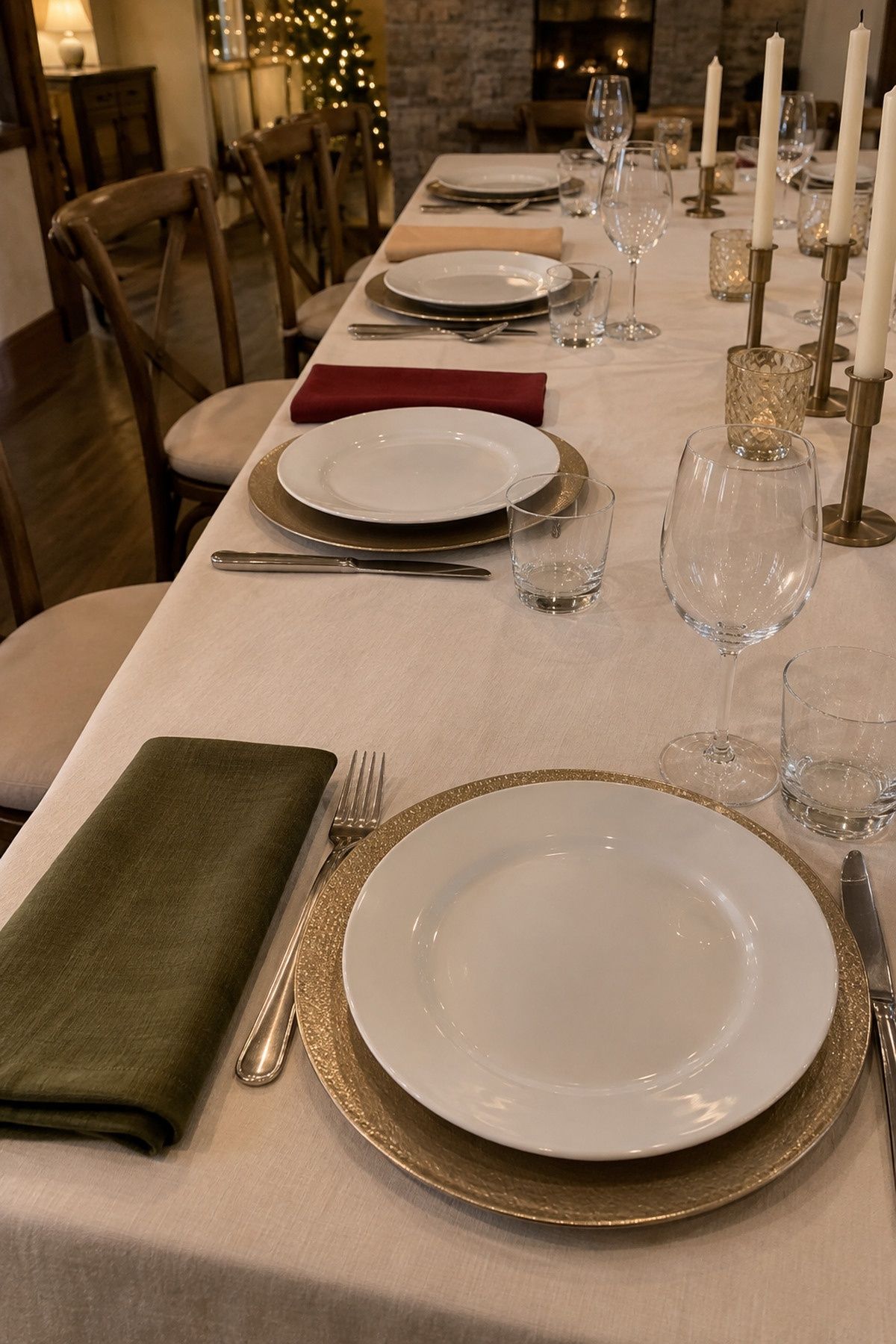 Cream linen tablecloth and simply folded warm-toned napkins at separate clean settings at an intimate Christmas wedding reception