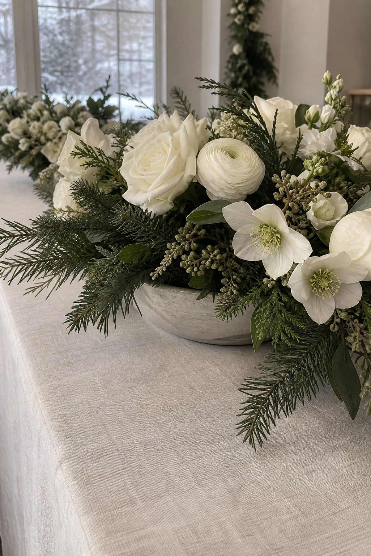 Low white floral bowls within a narrow evergreen centerline at an intimate Christmas wedding reception