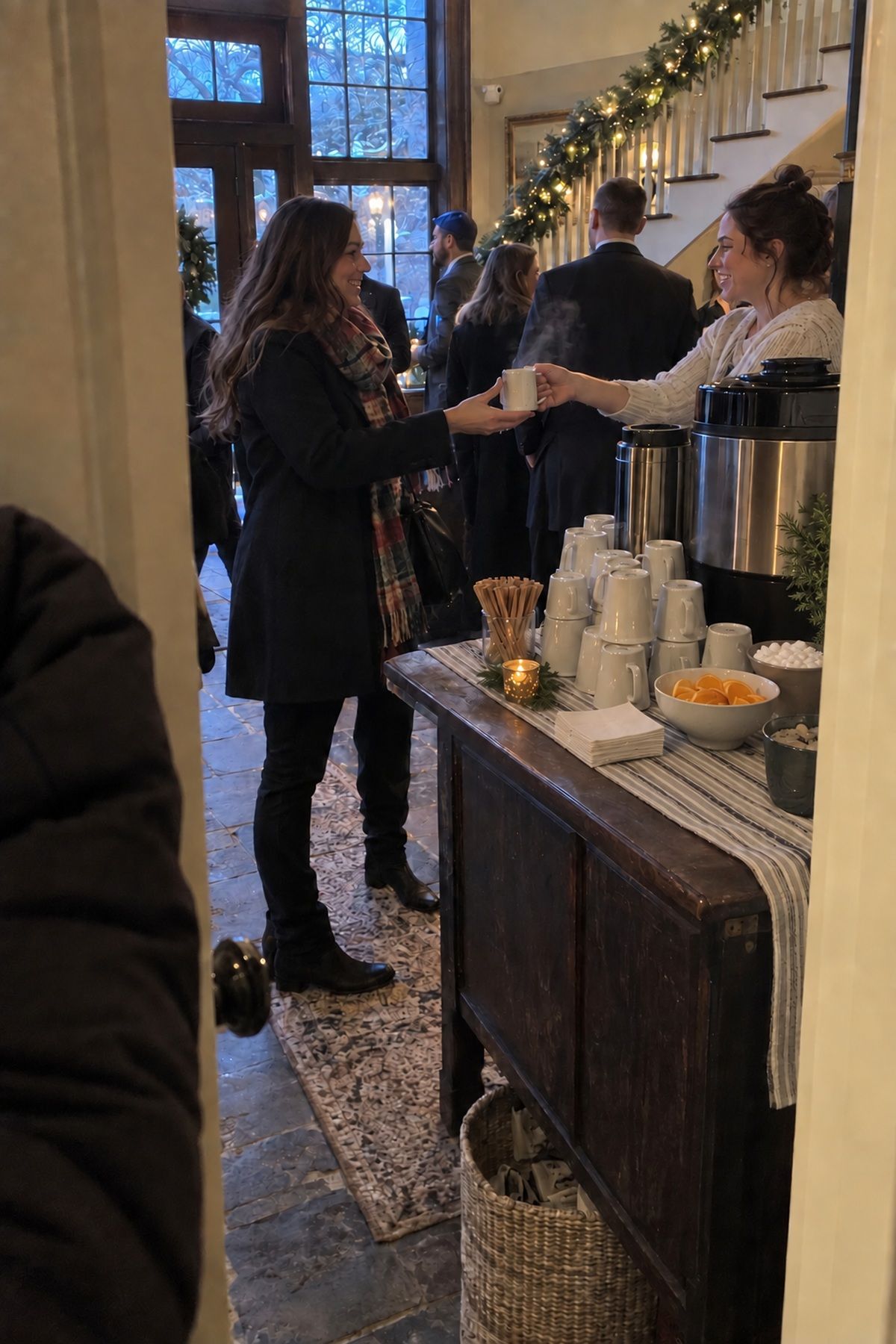 A winter wedding guest receives a hot drink at a compact foyer welcome bar.