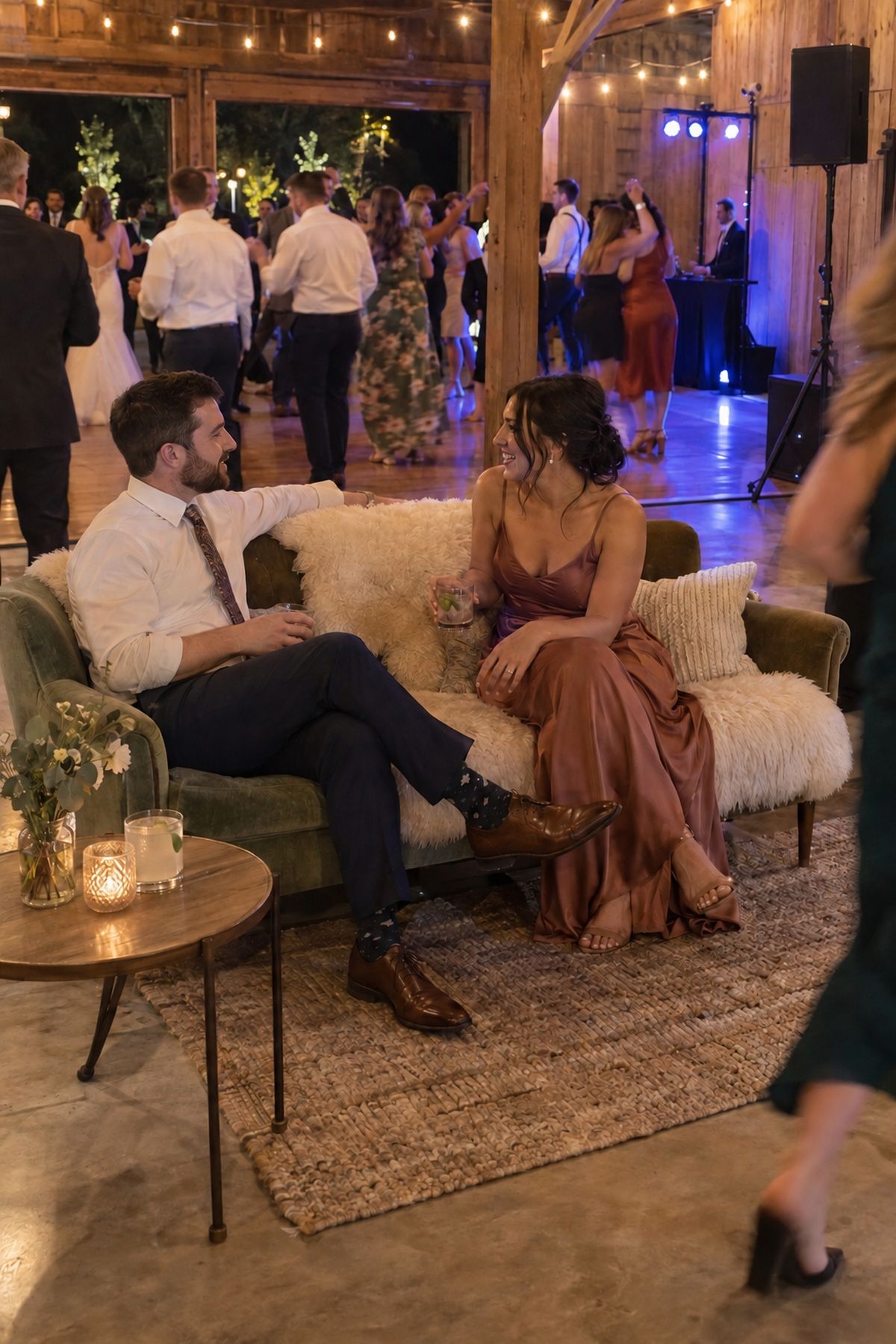 Guests talk on a warm lounge sofa beside an active winter wedding dance floor.