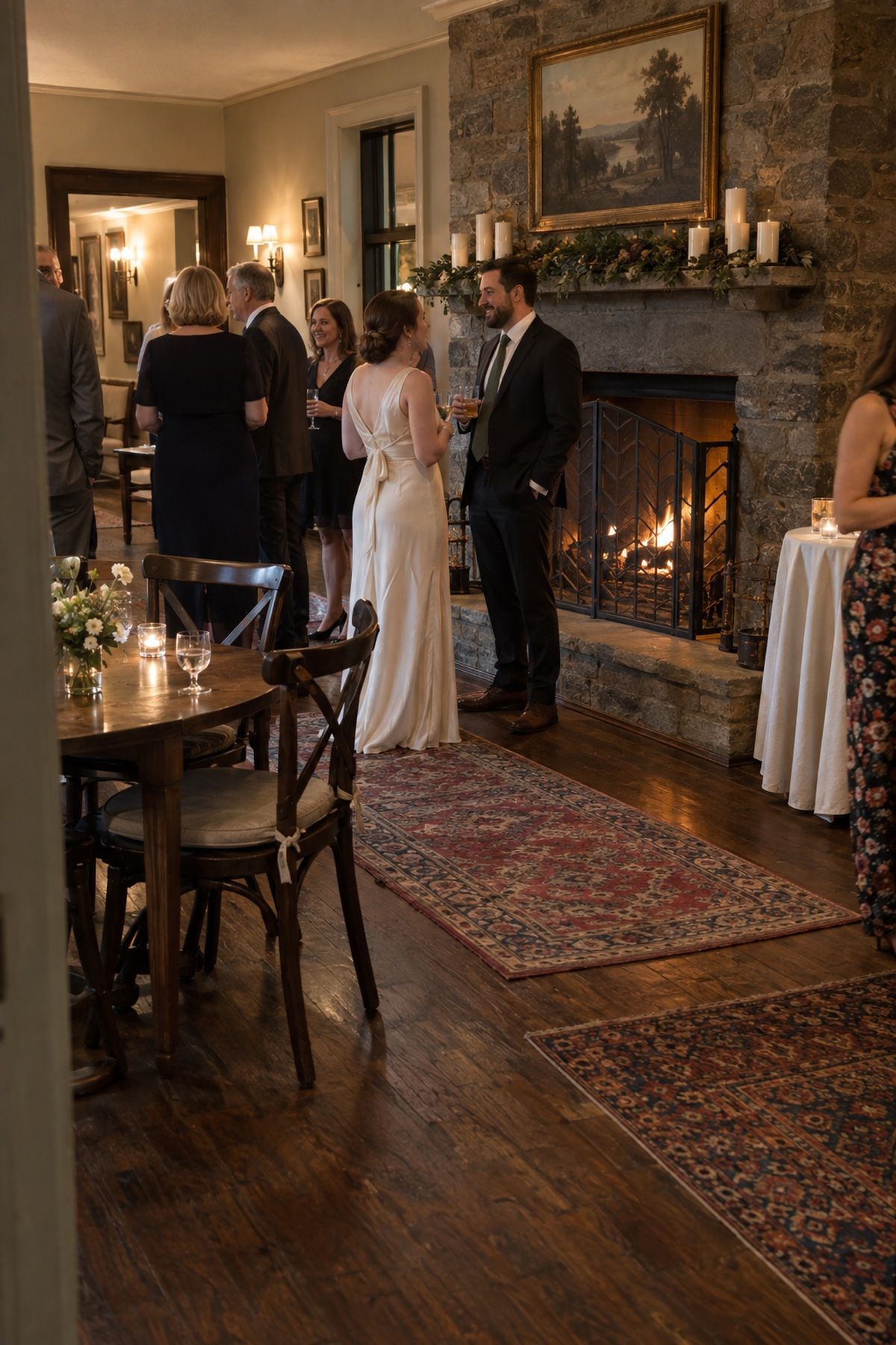 Wedding guests gather near a simply styled fireplace mantel in a historic inn.