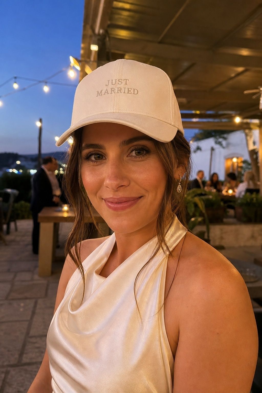 Bride dancing in a personalized cream baseball cap at a wedding after-party