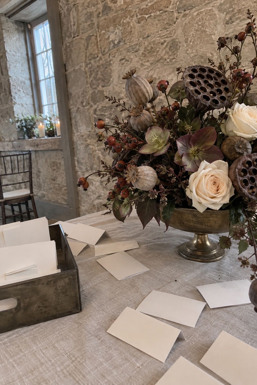 Lotus and poppy seed pods with hellebores and cream roses at a December wedding
