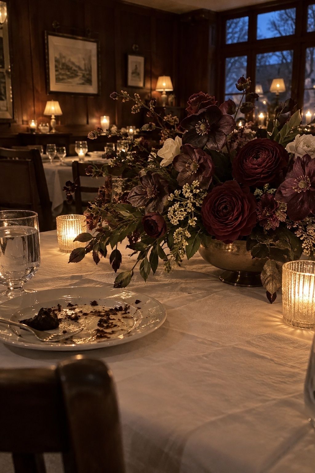Plum hellebores and merlot roses in a candlelit December sweetheart table centerpiece