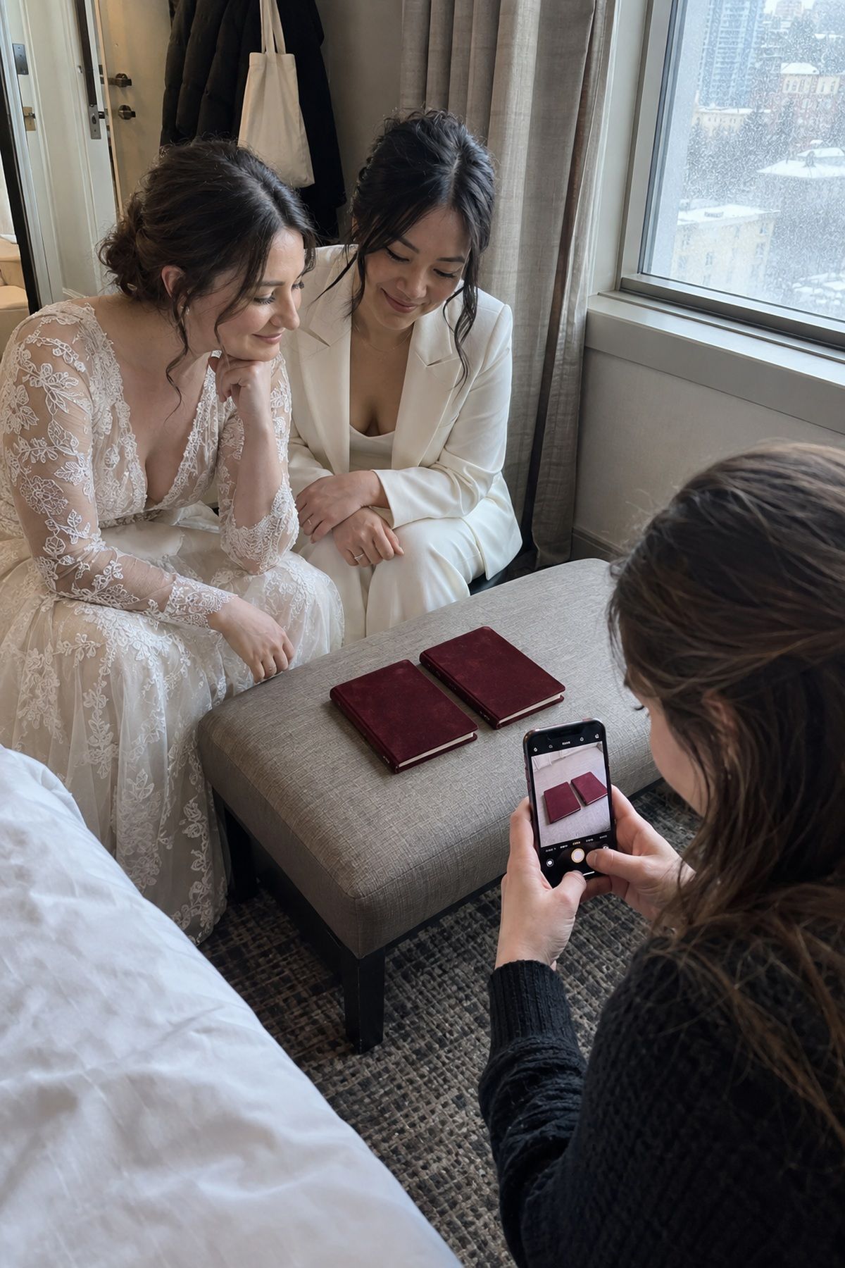 A friend photographs two blank velvet vow books before a December wedding ceremony.