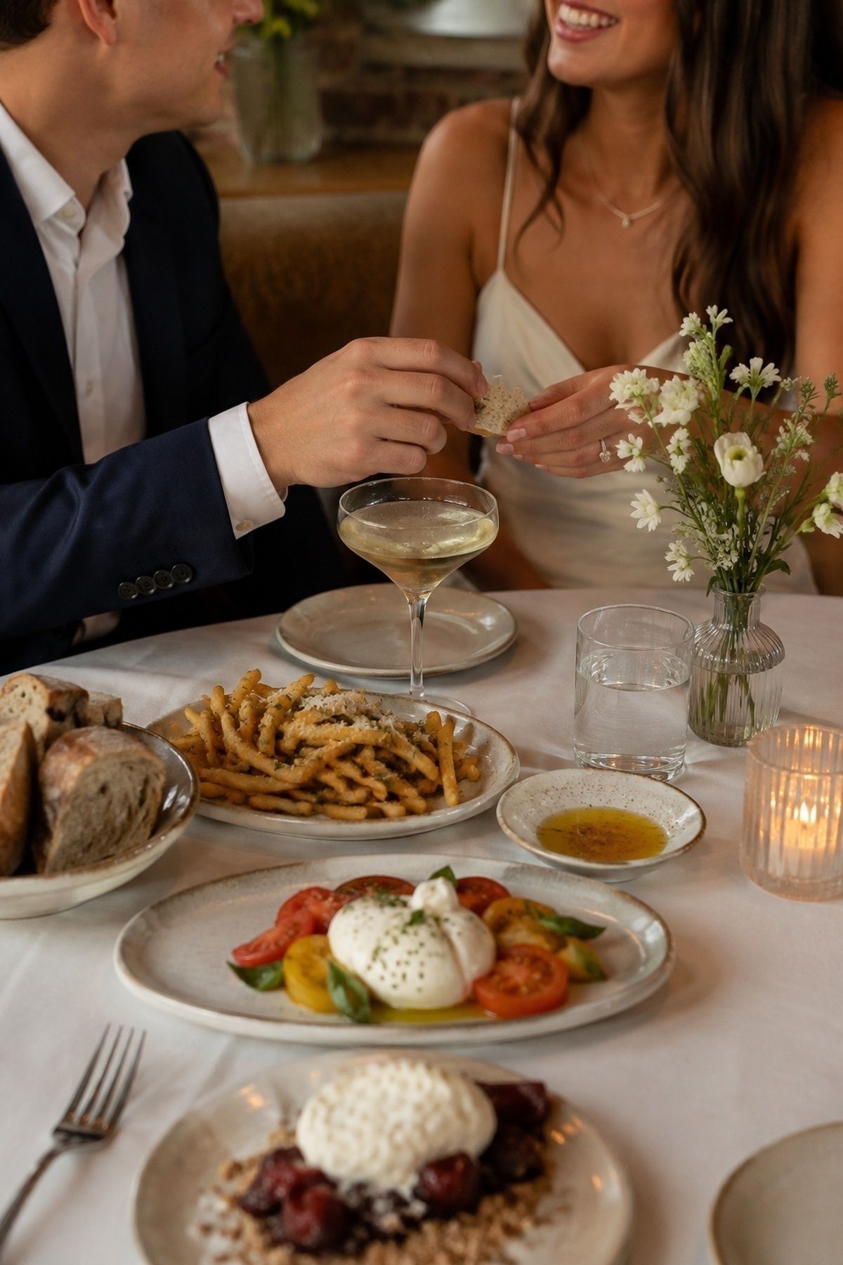 Restaurant engagement session table with easy small plates, bread, fries, dessert, and a relaxed couple
