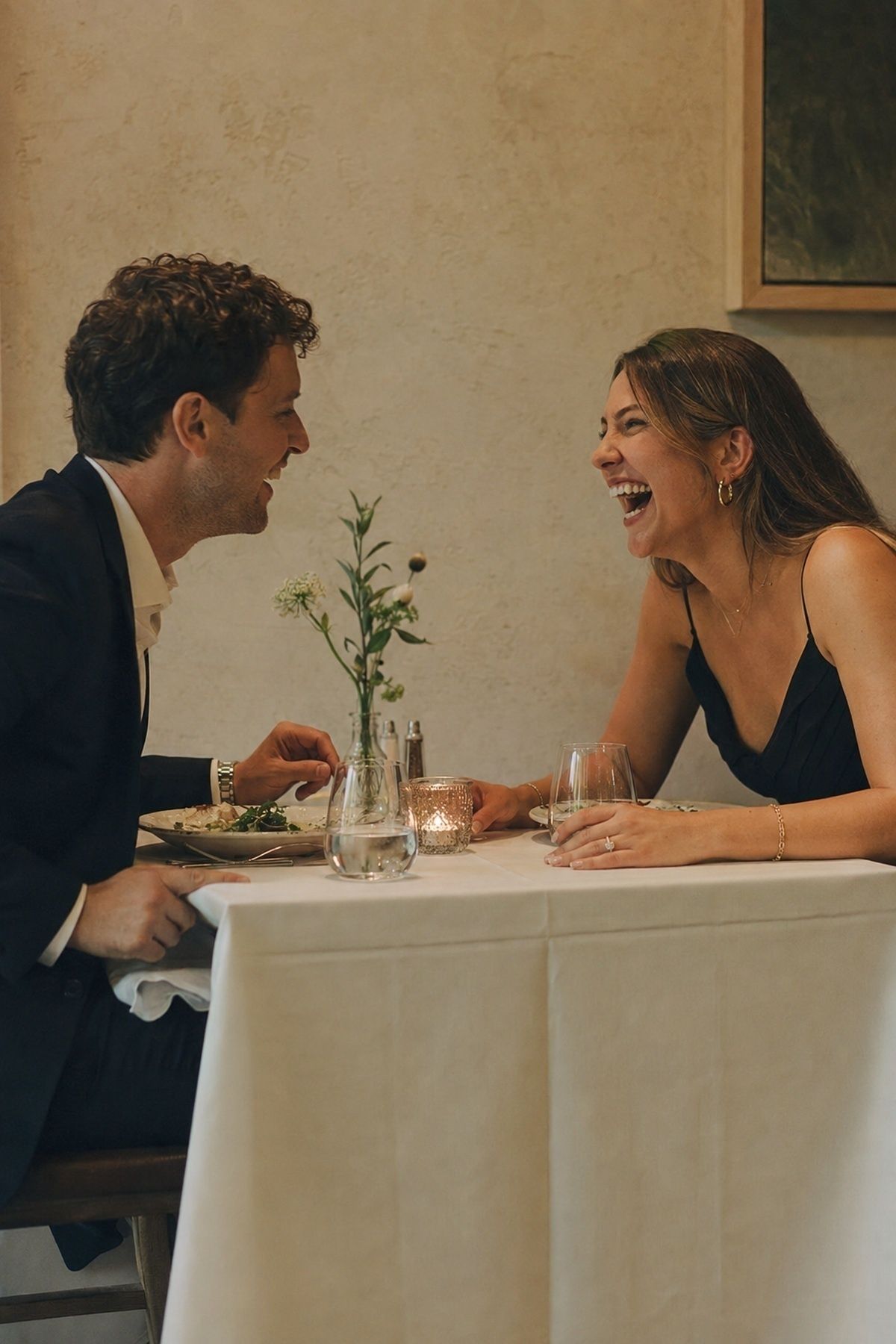Dinner date engagement couple laughing naturally across a small restaurant table