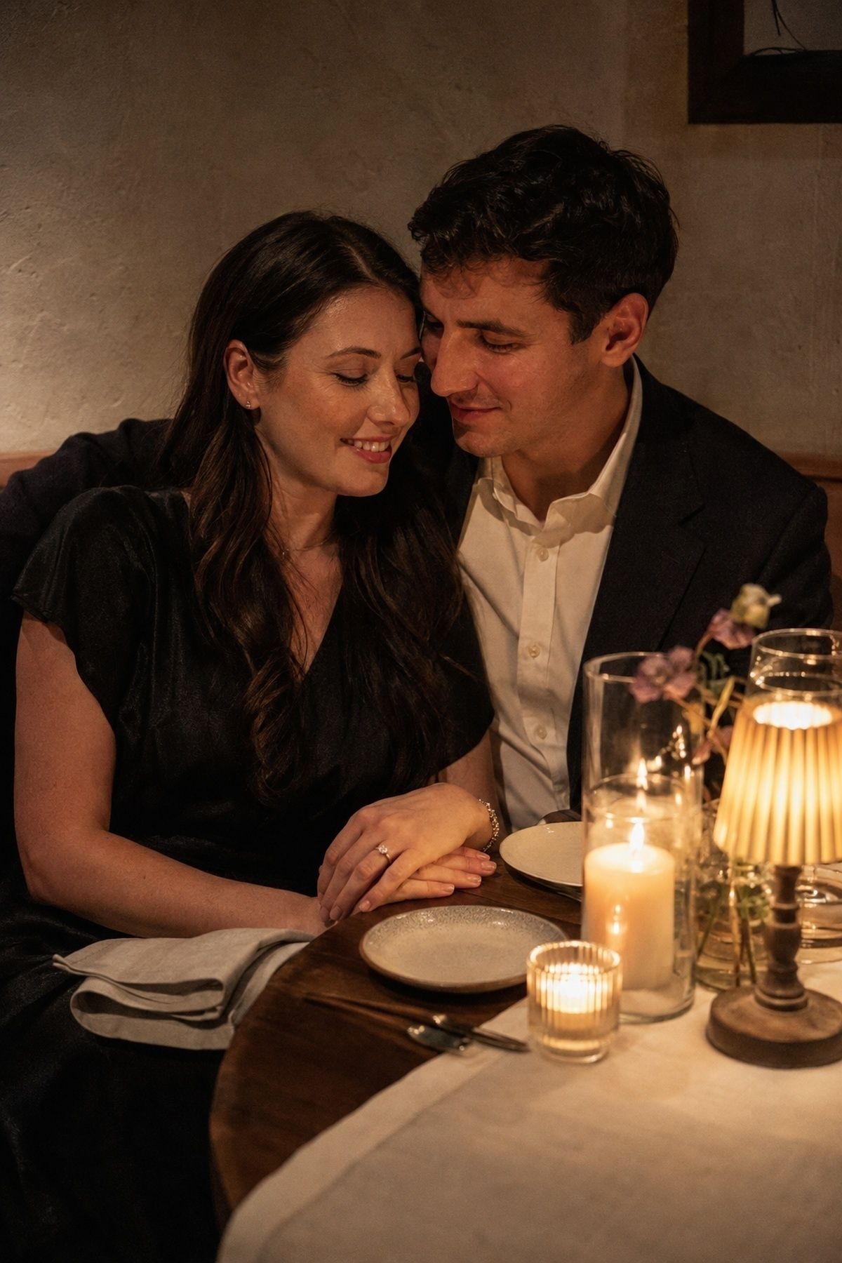 Dinner date engagement couple in a booth with side candlelight and readable faces
