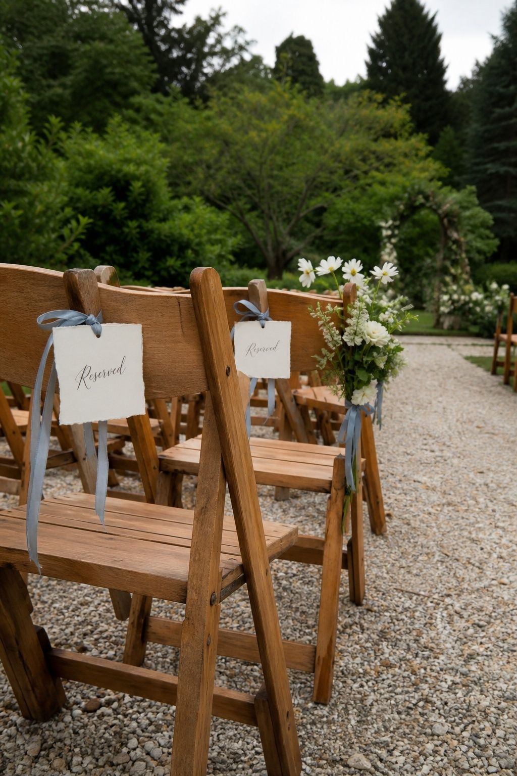 Reserved garden ceremony chairs with handwritten tags, blue ribbons and white flowers