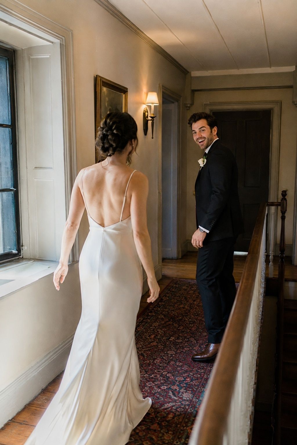 Groom turning with a spontaneous smile during an uncrowded hallway first look