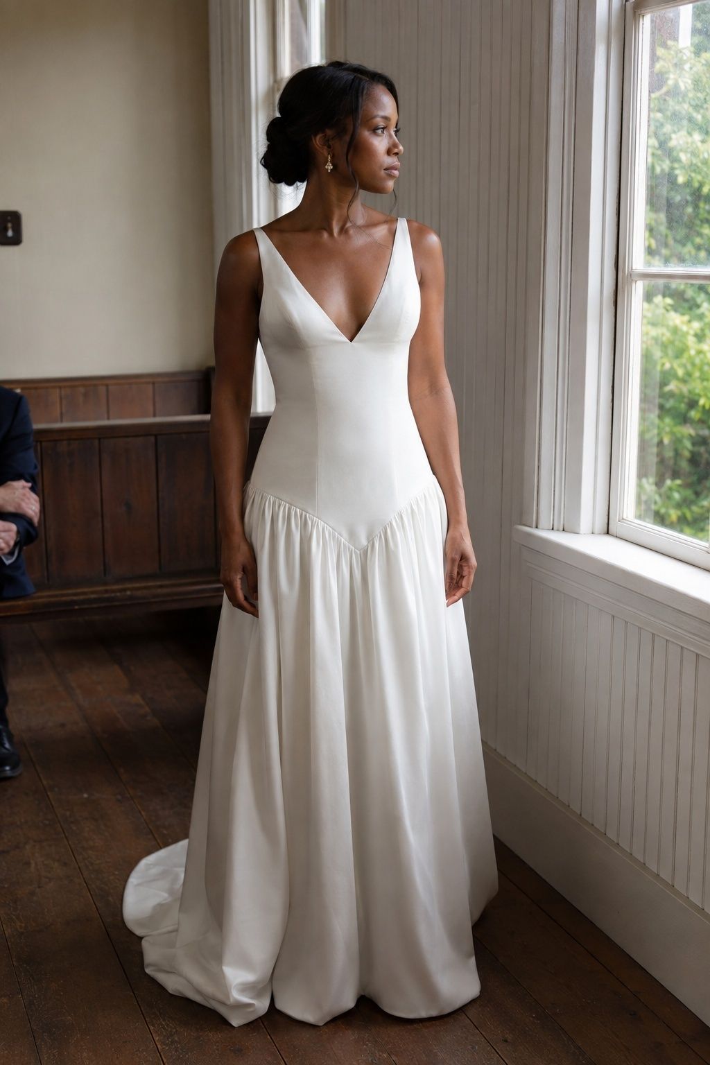 Bride wearing a pointed basque waist gown beside a chapel window