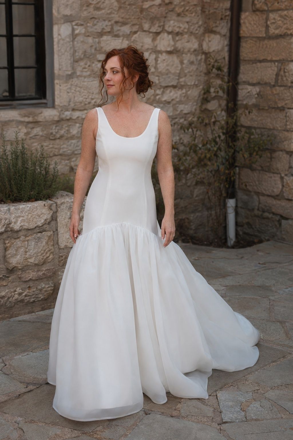 Drop waist ball gown with a full organza skirt in a stone courtyard