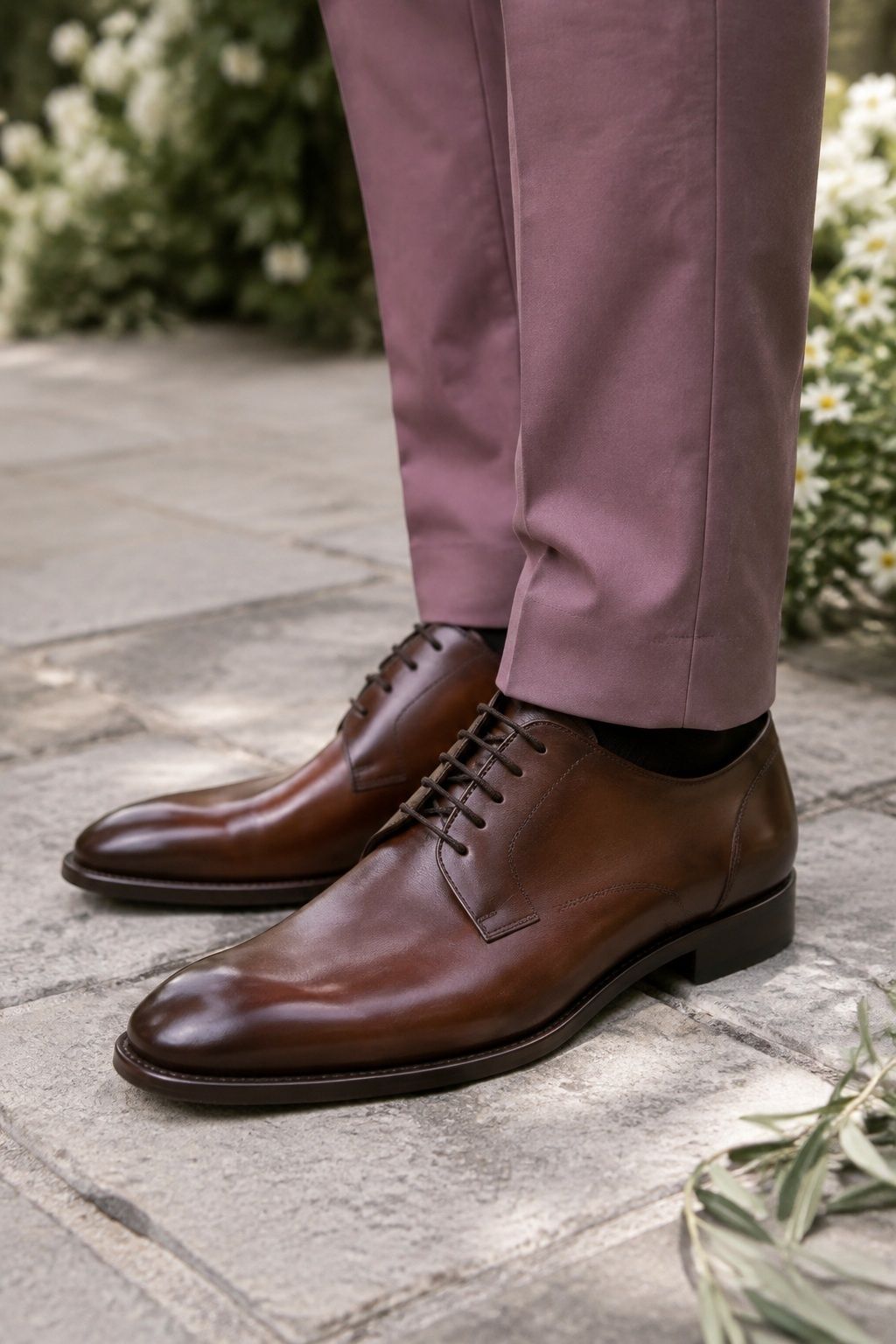 Chestnut brown derby shoes beneath tailored dusty rose trousers.