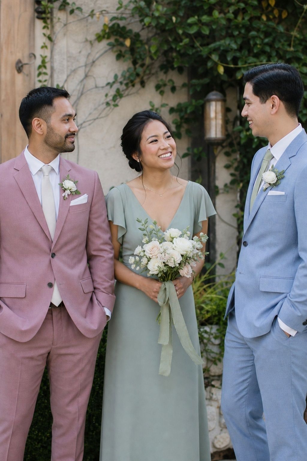 Dusty rose groom suit balanced by sage and pale blue wedding-party outfits.