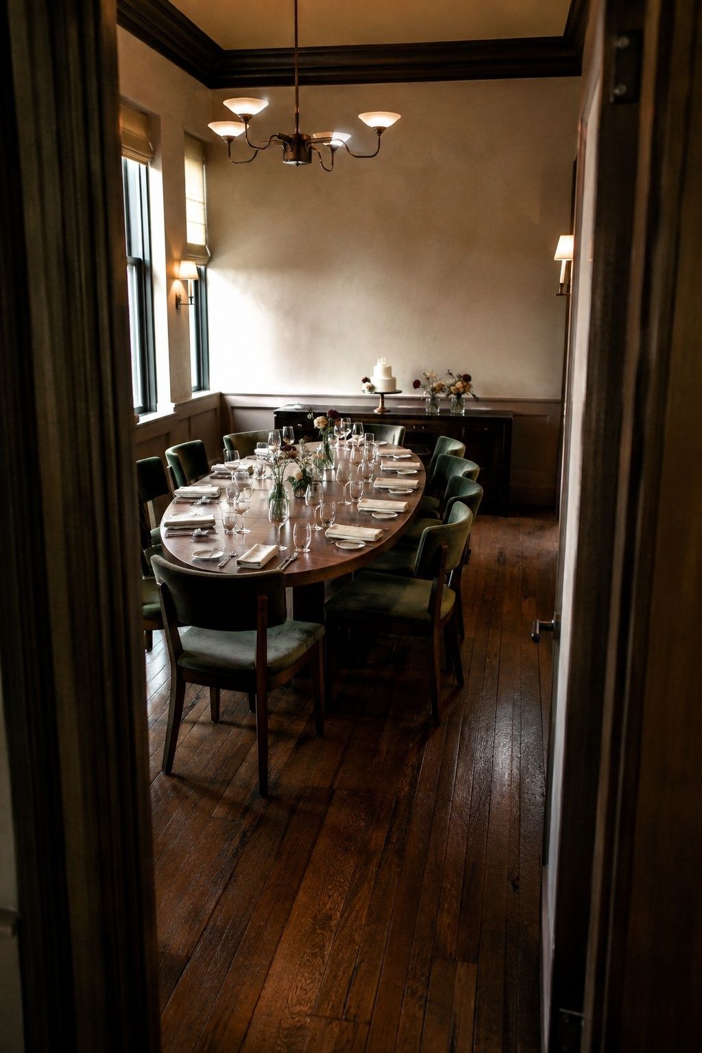 Private restaurant dining room with a walnut table, green chairs and a small wedding cake