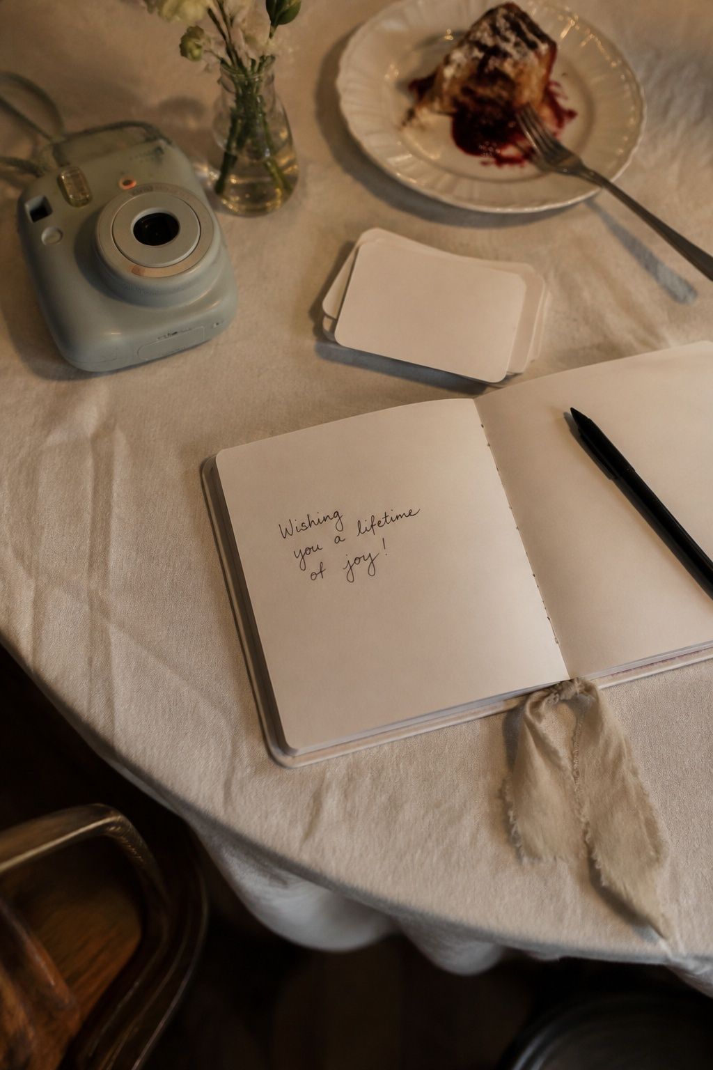 Instant camera and guest book beside an intimate wedding dinner table