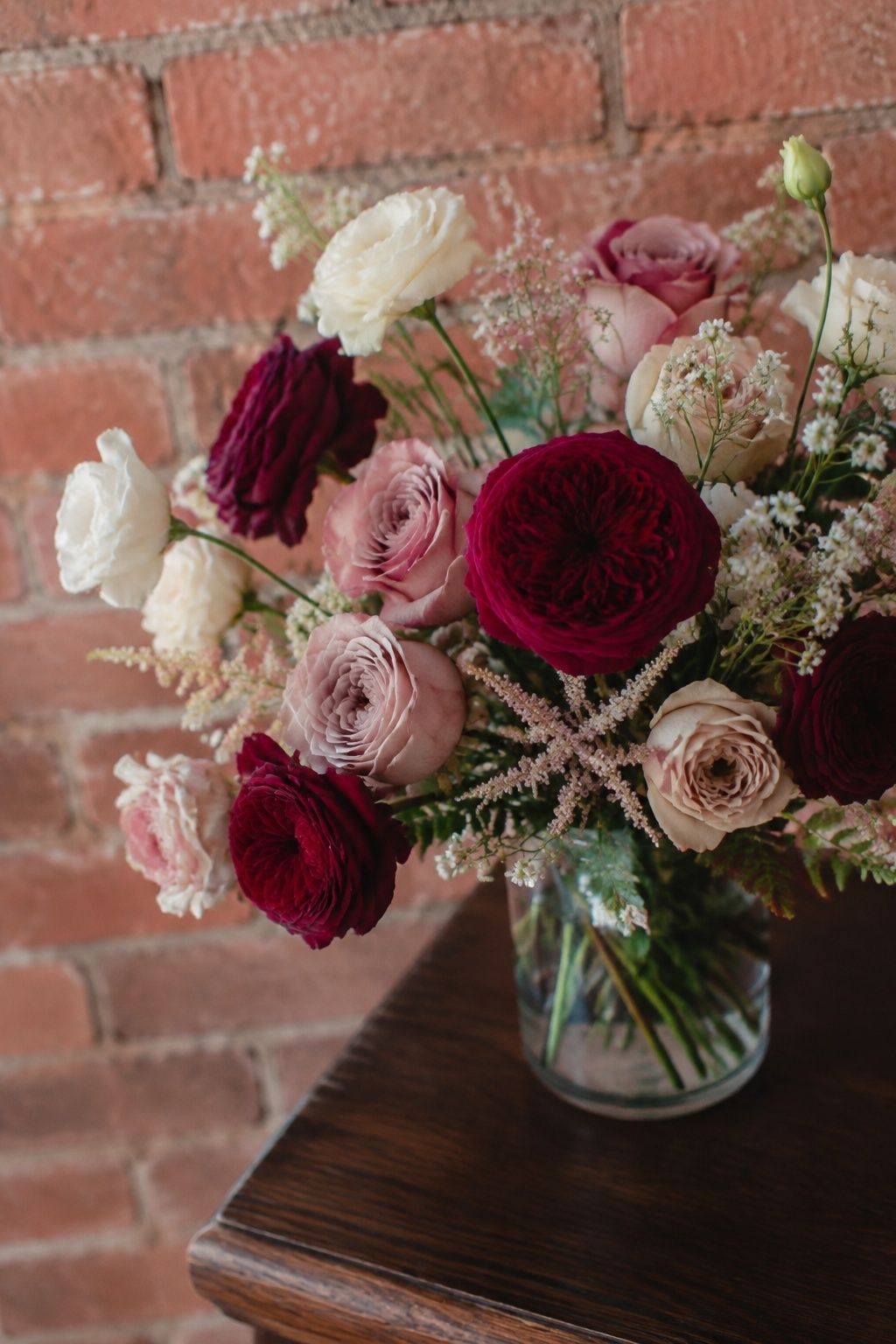 Burgundy roses with blush and mauve flowers in a bridal bouquet