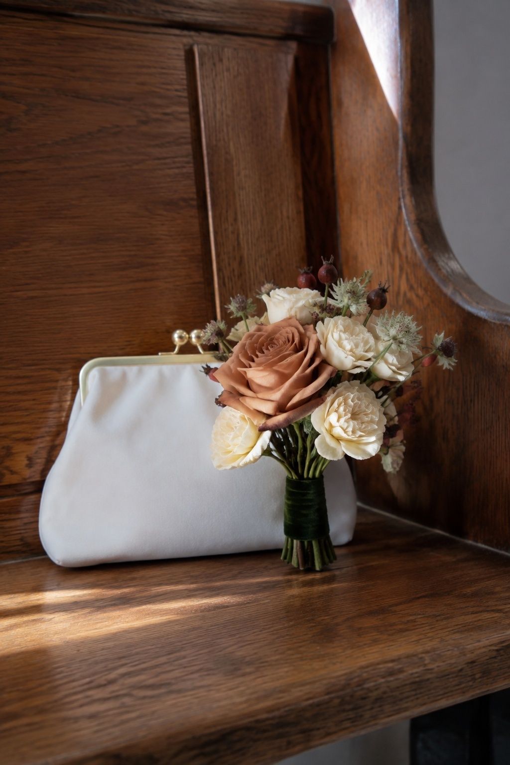 Petite copper and cream bridal posy beside an ivory clutch