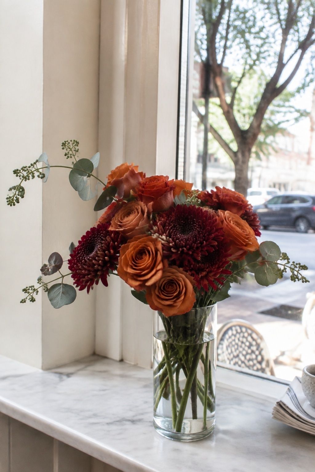 Seeded eucalyptus extending from a terracotta and burgundy bouquet