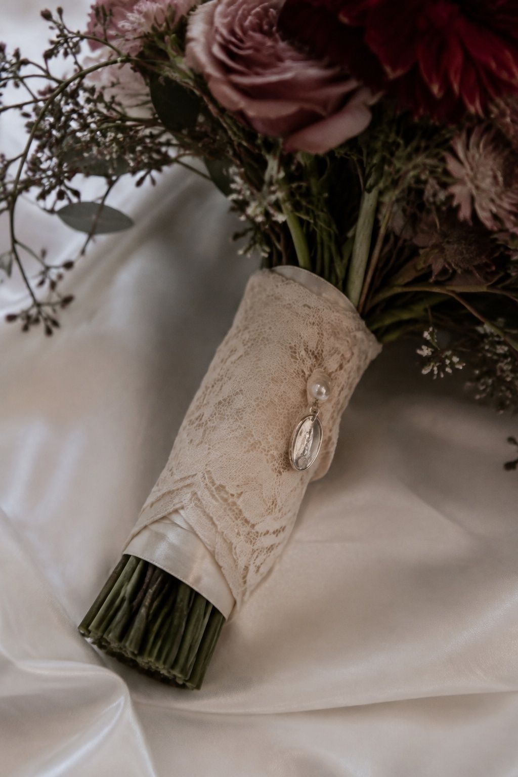 Heirloom lace and a small charm wrapped around bouquet stems