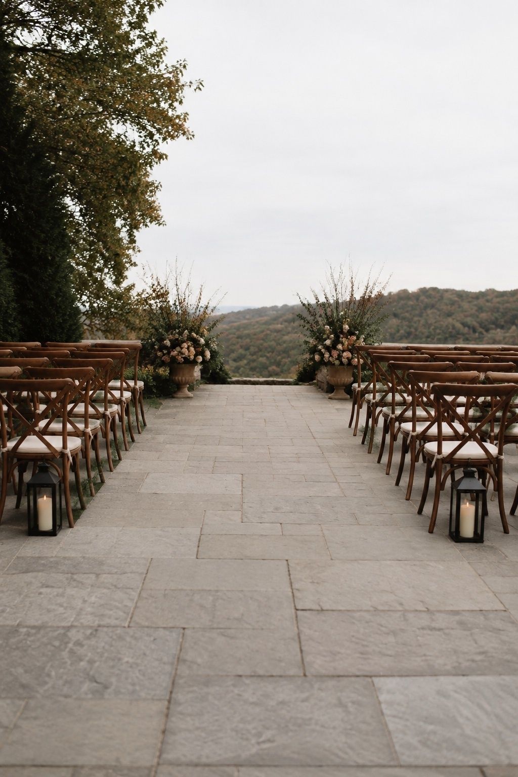 Low enclosed lanterns outside a wide stone wedding aisle