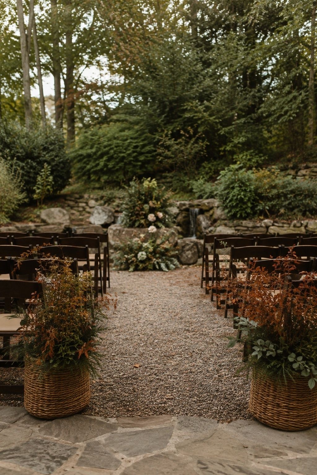 Two low foliage baskets framing the back row of ceremony chairs