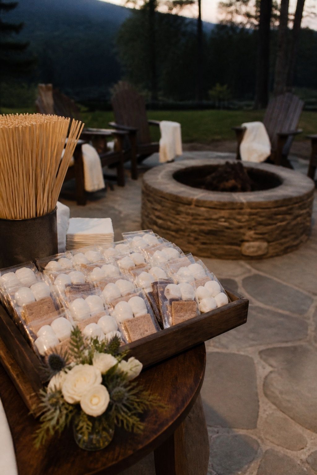 S’mores favor kits beside roasting sticks at a lodge fire pit