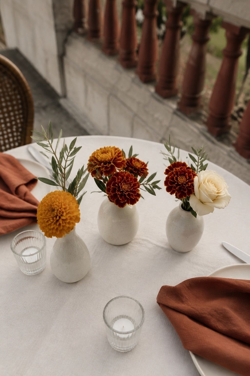 Orange and gold marigolds in small cream bud vases