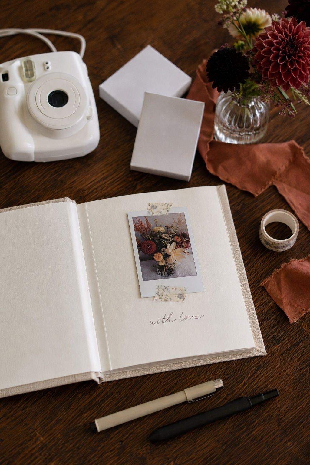 Instant camera and open linen guest book with a taped photo and handwritten note