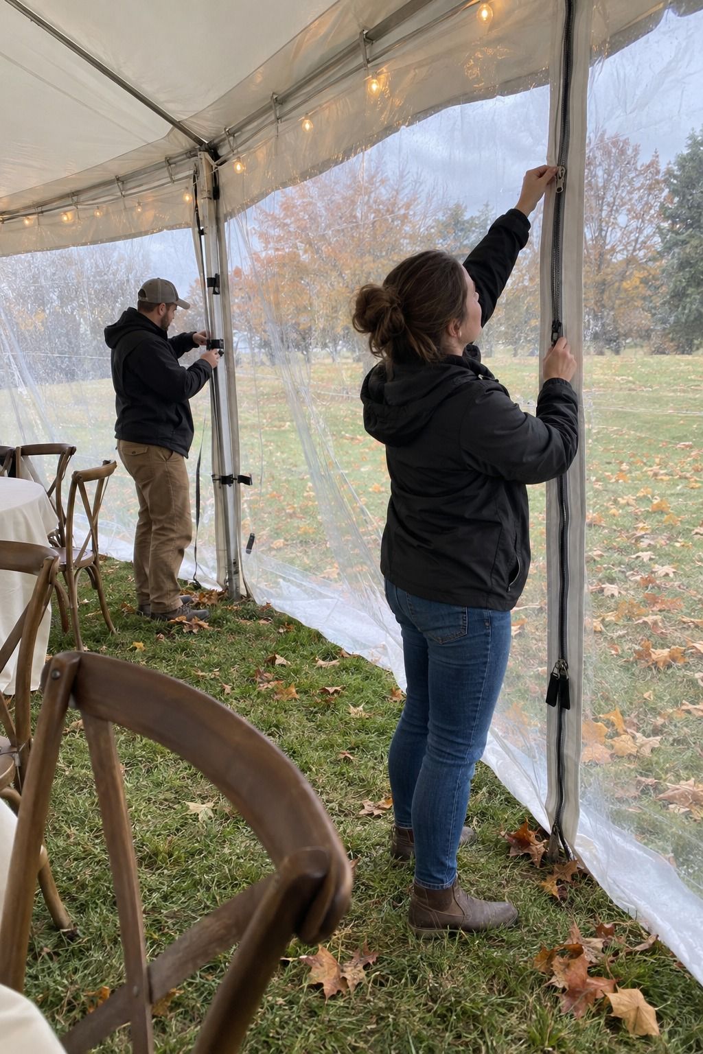 Rental helpers secure clear tent sidewalls for a windy forecast.