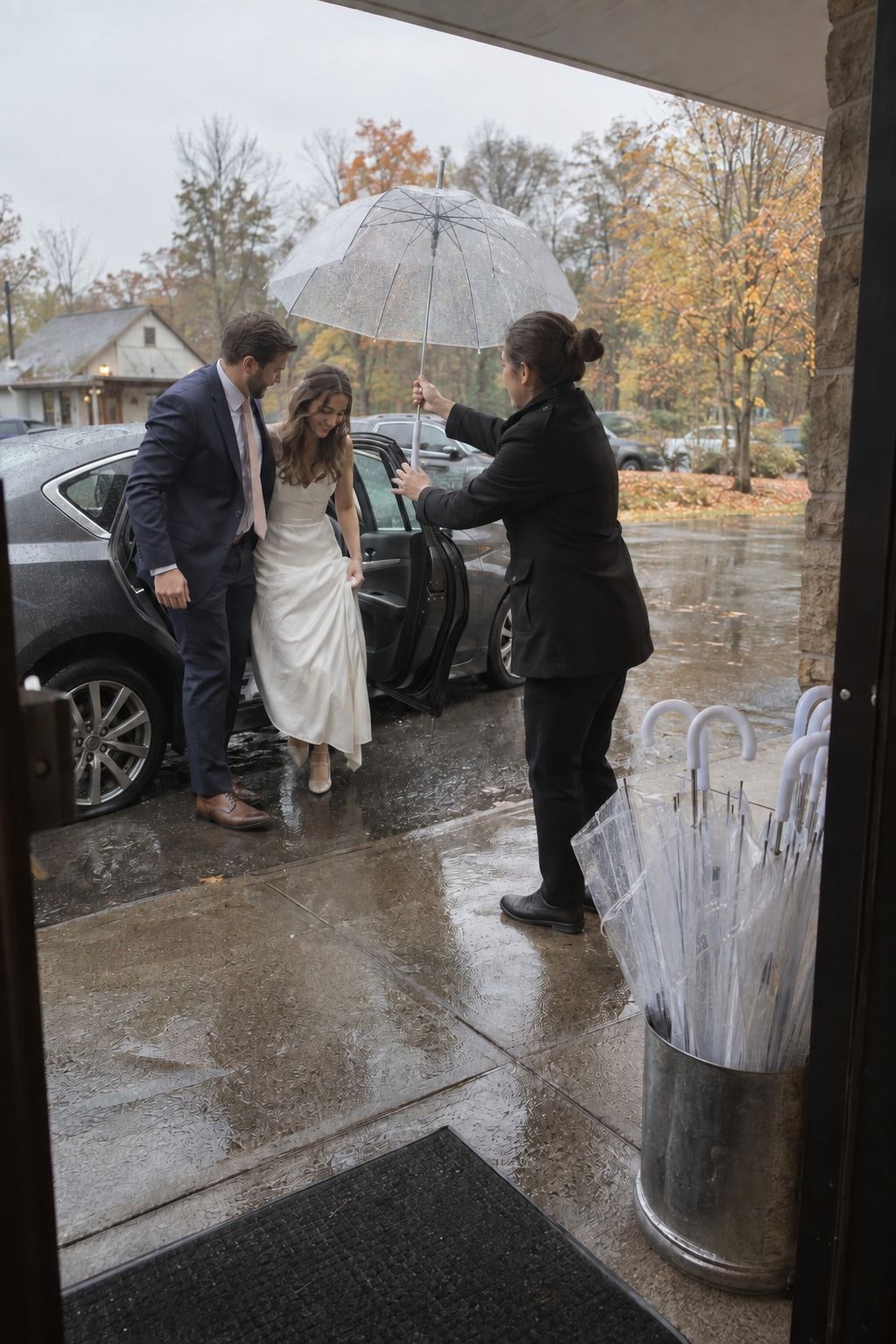 A clear umbrella handoff keeps the arriving couple covered in autumn rain.