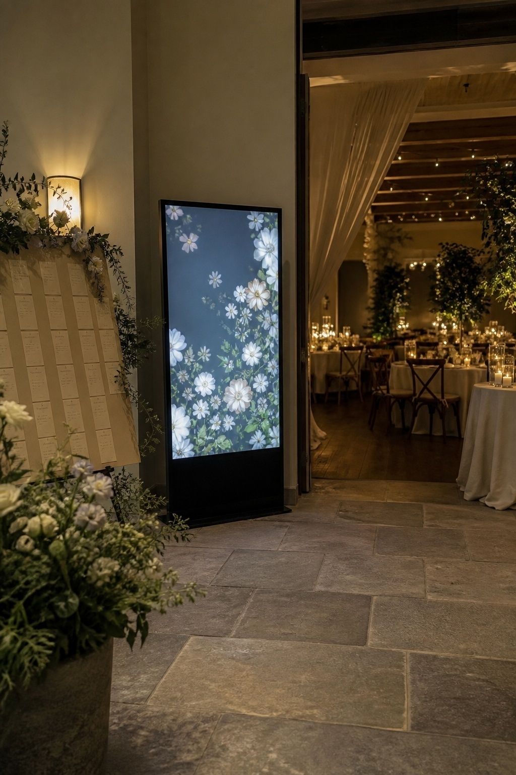 Animated floral screen placed near a seating chart at a wedding reception entrance